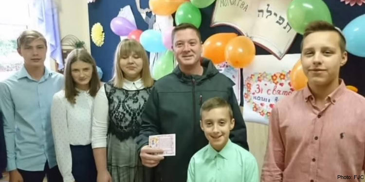 A group of people standing in front of a wall with balloons