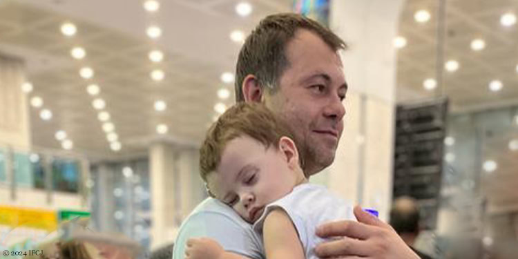 Man holding a sleeping baby to his shoulder