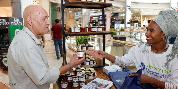 IFCJ staff passing out jars of honey to people in the mall