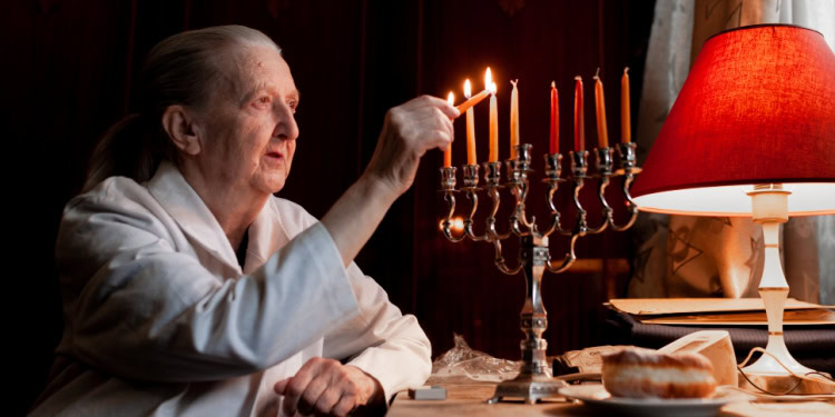 elderly woman sit with menorah and candles on table