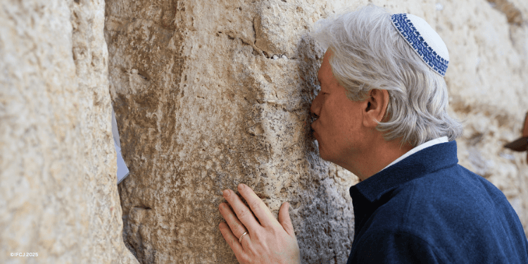 Bishop Lanier prays by and kisses the Western Wall.