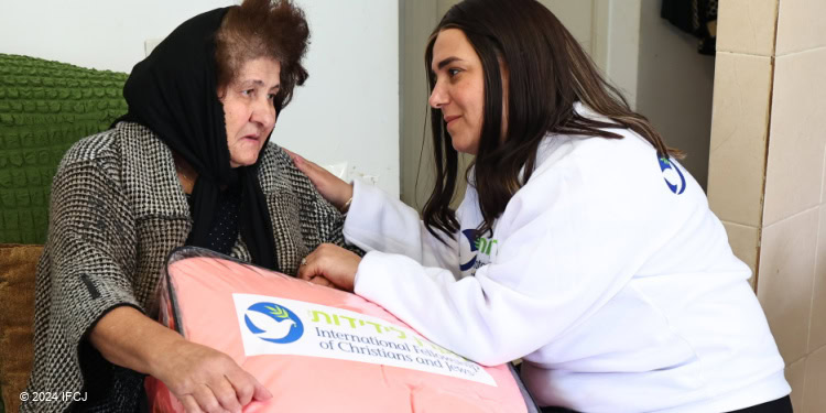 Elderly Ella and Fellowship Volunteer sit together with food box