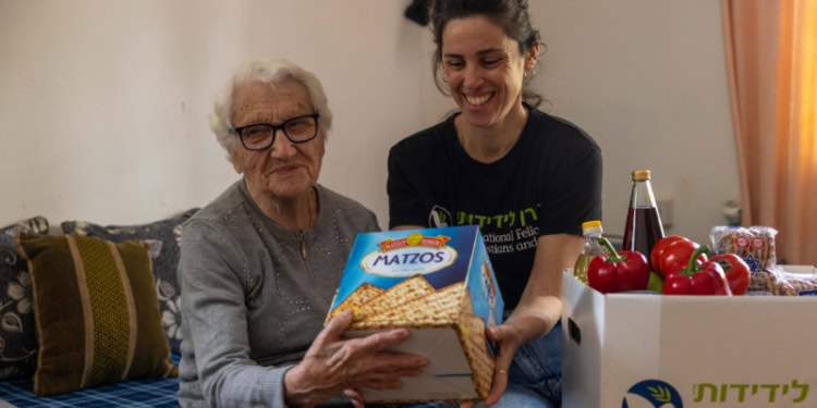 Volunteer takes a picture with Frida smiling. Holding up matzah bread.