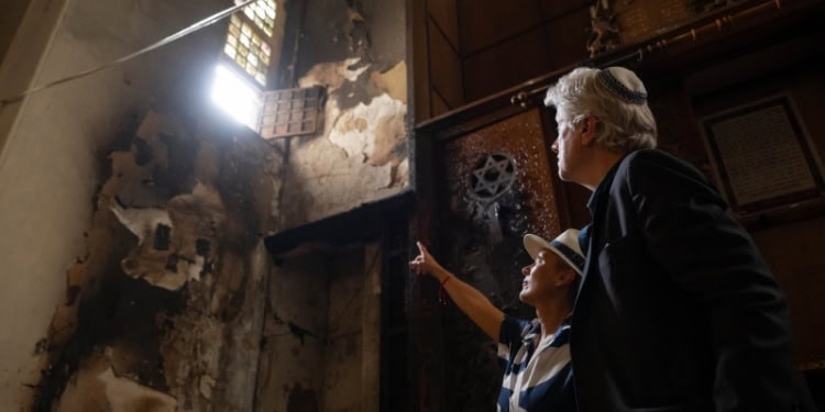 Bishop Lanier surveying damage inside of a French synagogue, with a guide.