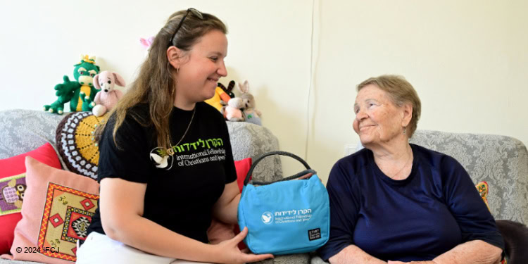 Fellowship volunteer handing an elderly woman a blue bag.