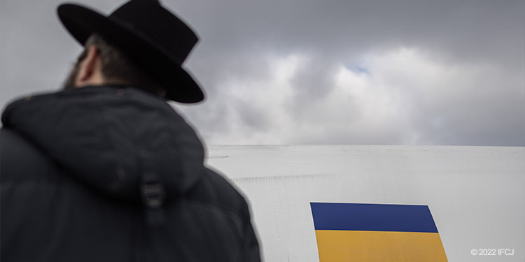 Ukrainian refugee outside next to airplane