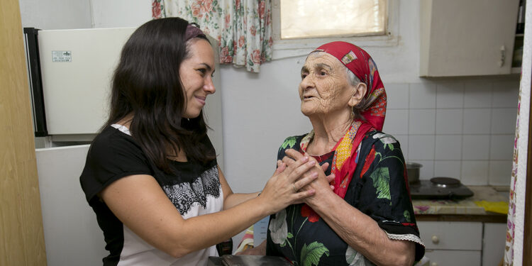 Yael Eckstein holding the hand of an elderly woman.