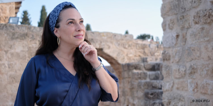Yael Eckstein standing outside, wearing a blue shirt, staring into the distance.