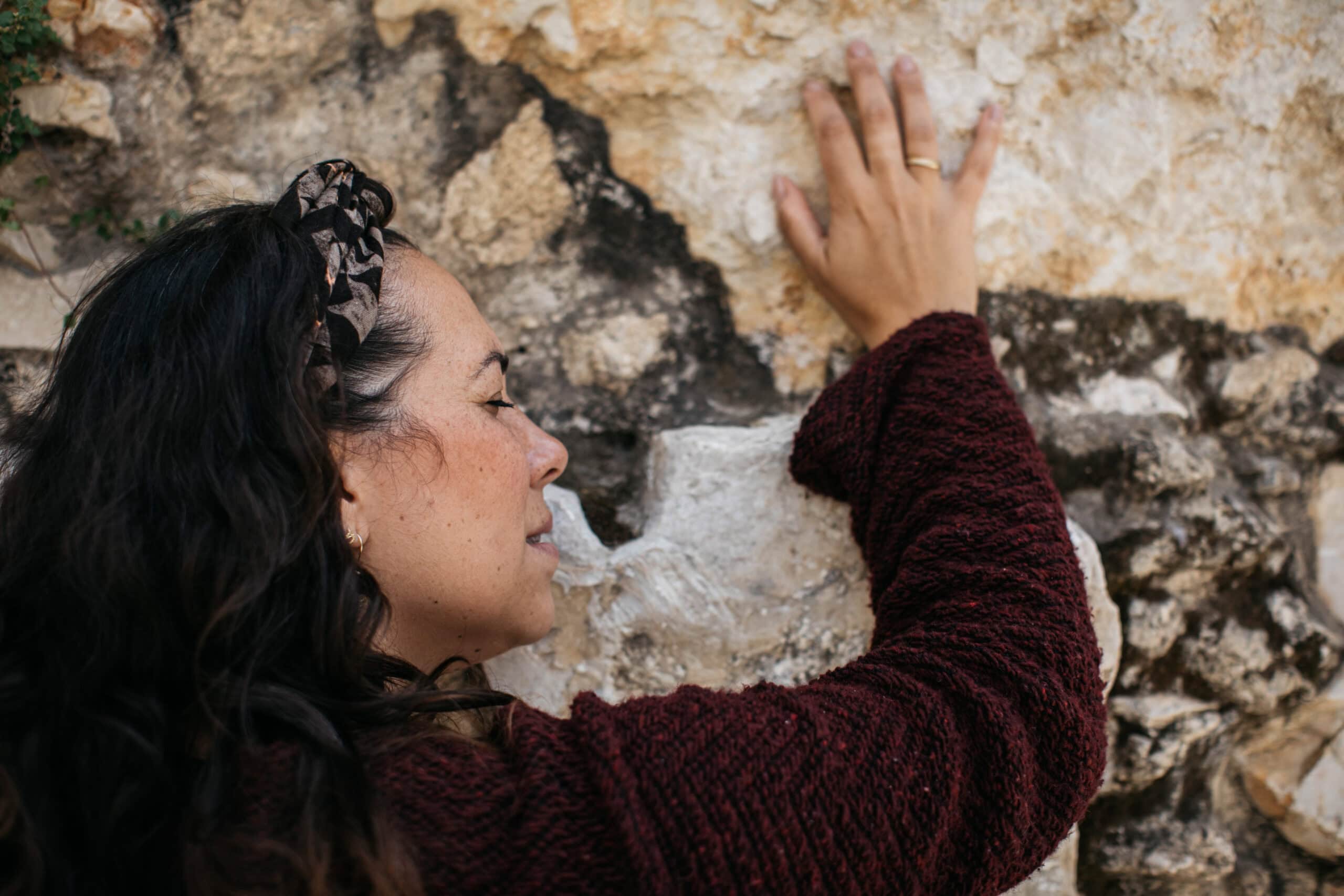 Yael Eckstein at the Western Wall,  April 12, 2021, Yael leans her cheek and hand against the wall with eyes closed, black shirt