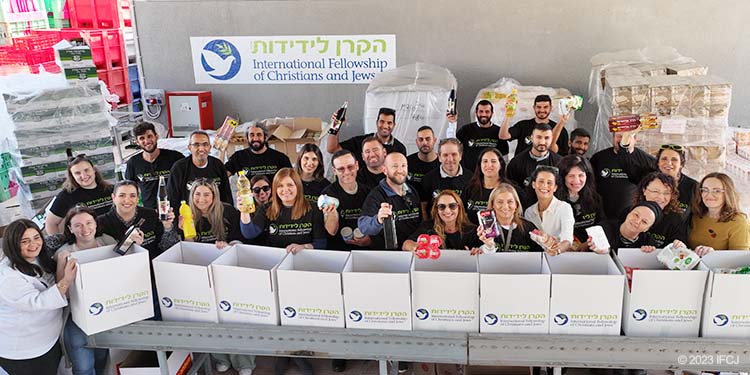 IFCJ-Israel staff members stand near assembly line packing food boxes