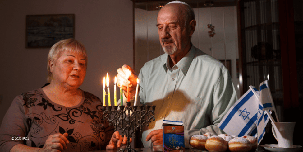 Isaak and Isabela Zendel celebrating Hanukkah and lighting a menorah together.