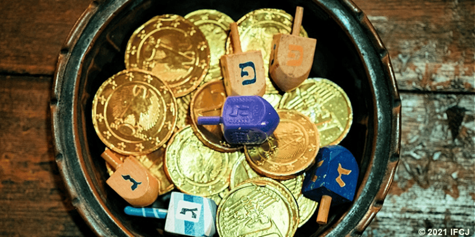 A bowl of dreidels and gold chocolate coins for Hanukkah.