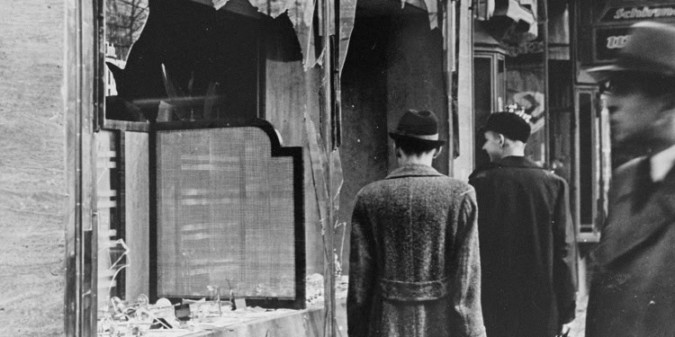 Black and white image of people walking past damaged buildings