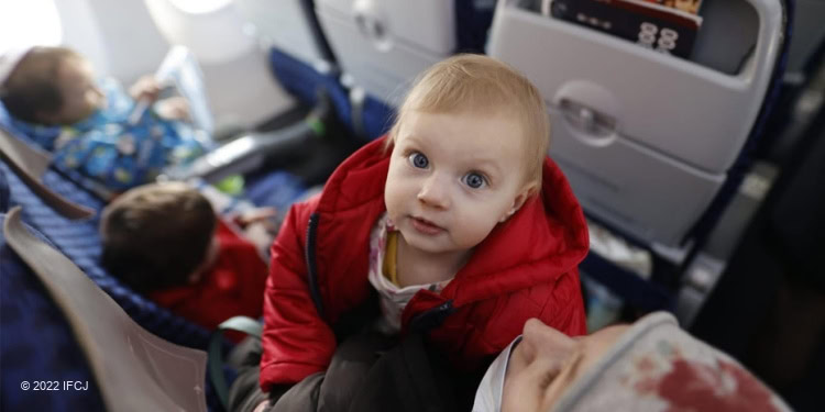 Ukrainian refugee flight, focus on baby looking at camera